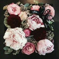 an arrangement of pink and red flowers on a black table with the name warf written on it