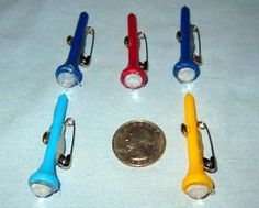 four different colored flashlights sitting next to a penny on a white tablecloth with a coin in the foreground