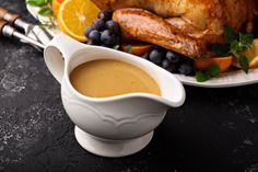 a turkey and gravy on a plate with oranges, blueberries, and grapes