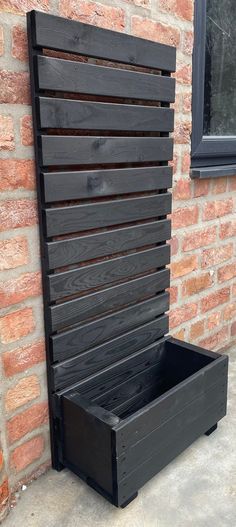 a wooden bench sitting next to a brick wall with a window in the back ground