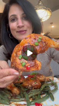 a woman holding up a piece of pizza in front of her face with green beans on it