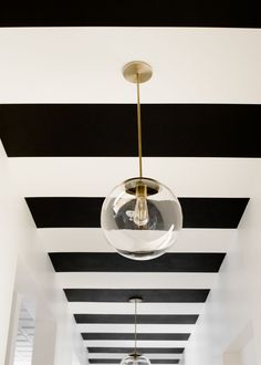 a black and white striped ceiling with a light fixture hanging from it's center