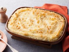 a casserole dish with cheese and bread on the side next to a fork