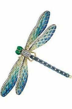 a blue dragonfly brooch sitting on top of a white surface with green accents