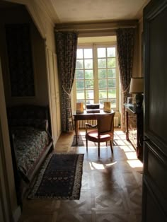 a bedroom with a bed, desk and chair in it's doorway way to another room