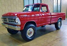 a red truck parked in a garage next to a brick wall with windows on it