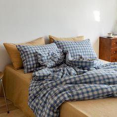 an unmade bed with blue and white checkered sheets