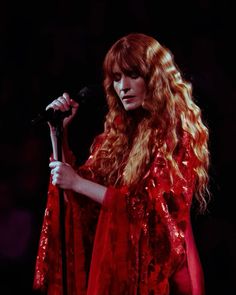 a woman with long red hair holding a microphone