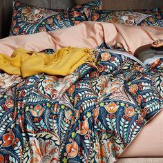 an unmade bed with blankets and pillows on top of it, in front of a wooden headboard