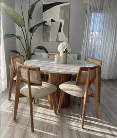 a dining room table with four chairs and a potted plant in the corner on the side