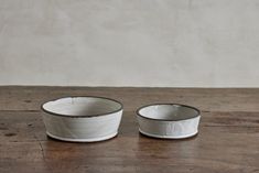 two white bowls sitting on top of a wooden table