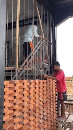 two men working on the side of a building made out of wood planks and metal bars