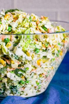 a large glass bowl filled with salad on top of a blue cloth