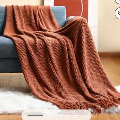 a couch with a blanket on top of it next to a white sheepskin rug