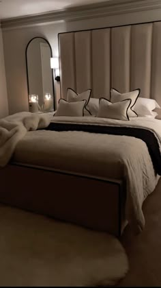 a bedroom with a large bed, mirror and candles on the nightstands in front of it