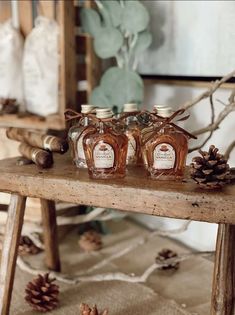 two bottles of honey sit on a table with pine cones and other items around it