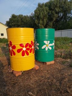 two large yellow and green barrels sitting in the dirt