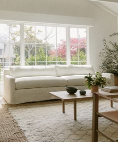 a living room filled with furniture next to a large white window covered in lots of windows