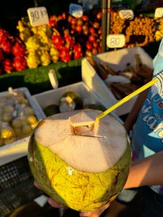 a person is holding an apple in front of some fruit at a market with other fruits behind them