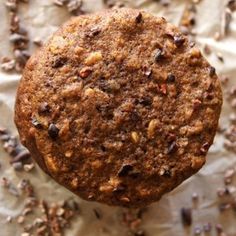 a close up of a muffin on a piece of paper with seeds scattered around it