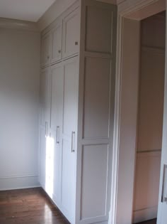 an empty room with white cabinets and wood floors