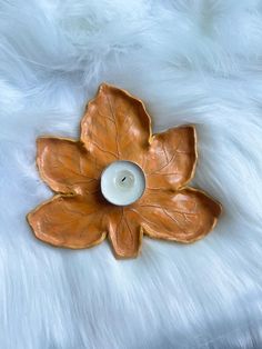 a candle that is sitting on top of a white fur covered surface with a flower shaped candle holder