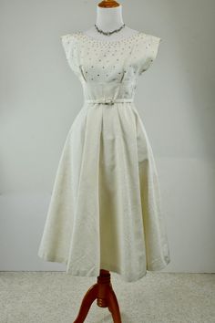 Stunning 1950s ivory moire party dress with pronged rhinestones, belted & fitted waistline, gored flaring skirt, comes with a short bolero jacket with dolman 3/4 cuffed sleeves that happens to button in back! Dress has metal side zipper, and insert pockets in side seams. Ensemble is not lined. BEAUTIFUL! LABEL: none CONDITION: excellent / dress has a 3 millimeter light brown spot next to side zipper / jacket has subtle arm pit staining both sides seen on close inspection only MEASUREMENTS: D Elegant Vintage White Dress For Party, Elegant Vintage White Party Dress, Elegant A-line Vintage Dress For Vintage Events, Elegant Vintage White Evening Dress, Evening Dress With Fitted Bodice In Vintage White, 1950s Style Cream Evening Dress, Vintage Cream Cocktail Dress, 1950s Style Cream Party Dress, 1950s Cream Party Dress