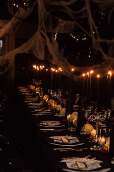 a long table is set with plates and candles for an elegant halloween dinner or party