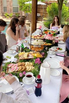 a group of people sitting around a table covered in food and drinks at a party