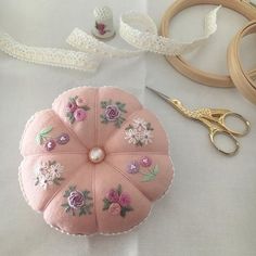 there is a pink flowered cushion next to some scissors and other crafting supplies