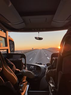 the sun is setting on an empty highway as seen from inside a vehicle's driver's seat