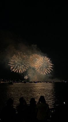 fireworks are lit up in the night sky over water