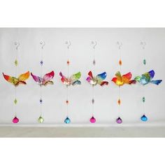 multicolored glass birds hanging from hooks on a white wall with ornaments in the shape of hearts