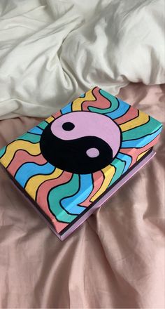 a book that is sitting on top of a pink bed sheet with an yin symbol painted on it