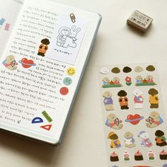 an open book with stickers on it next to a pen and eraser set