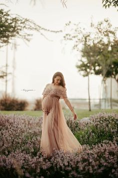 a pregnant woman standing in a field of lavenders with her hands on her hips