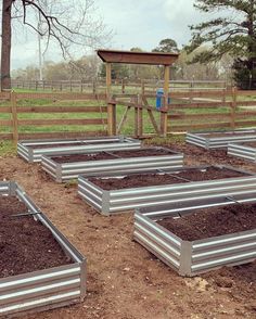 several metal boxes filled with dirt in front of a fence