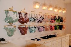 there are many bras hanging on the wall in this room with lights above them