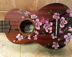 an ukulele with pink flowers painted on it's body and the strings