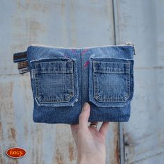 a person holding up a small denim pouch