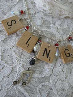 a necklace with musical notes on it and charms hanging from the clasp that says sing