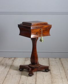 an old wooden table with a green tassel hanging from it's top on a wood floor