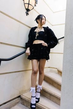 a young woman standing on the steps in front of a building wearing high heels and a crop top