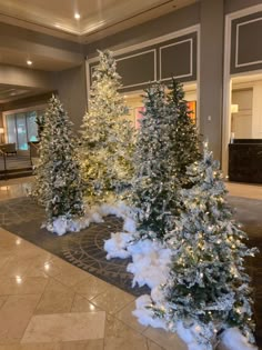 christmas trees are lined up on the floor in front of a hotel lobby entrance area