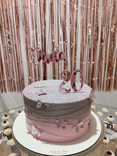 a pink and grey cake with the number 90 on it sitting on top of a table