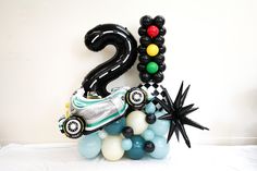 a number two balloon with cars and balloons in the shape of numbers on top of it