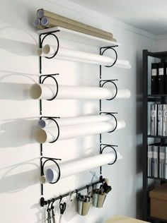 there is a wall mounted rack with cups and glasses on it in front of the bookshelf