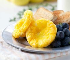 a breakfast plate with eggs, blueberries, toast and lemons on the side