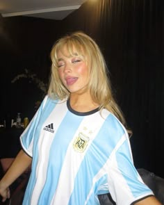 a woman in a blue and white soccer uniform posing for the camera with her tongue out