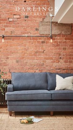 a blue couch sitting in front of a brick wall